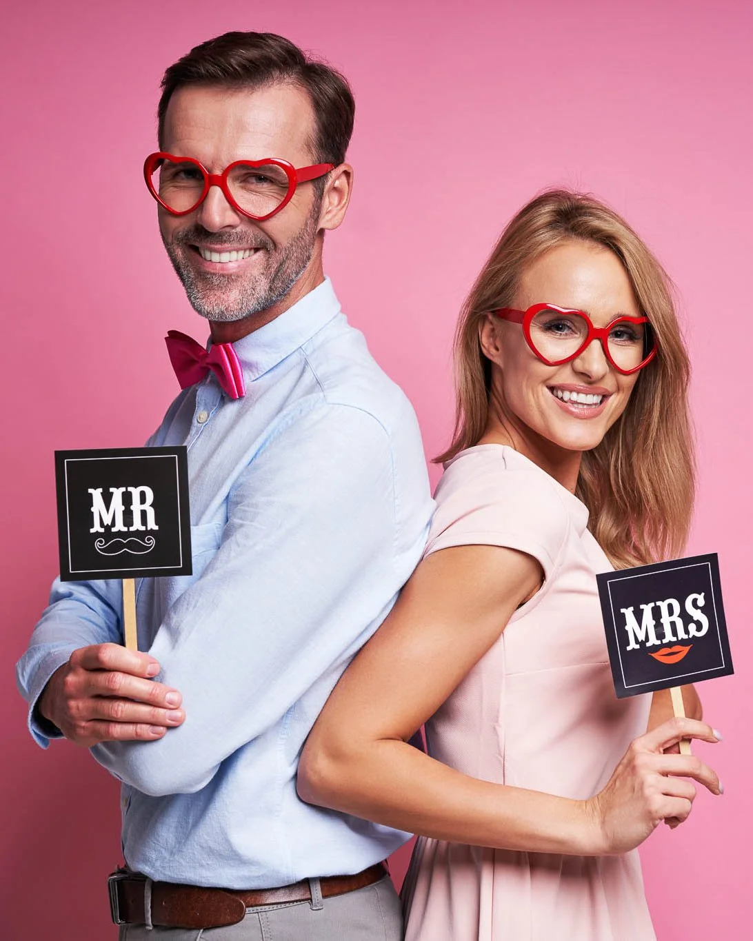 A engagement party event photo booth photo of a couple holding weding props