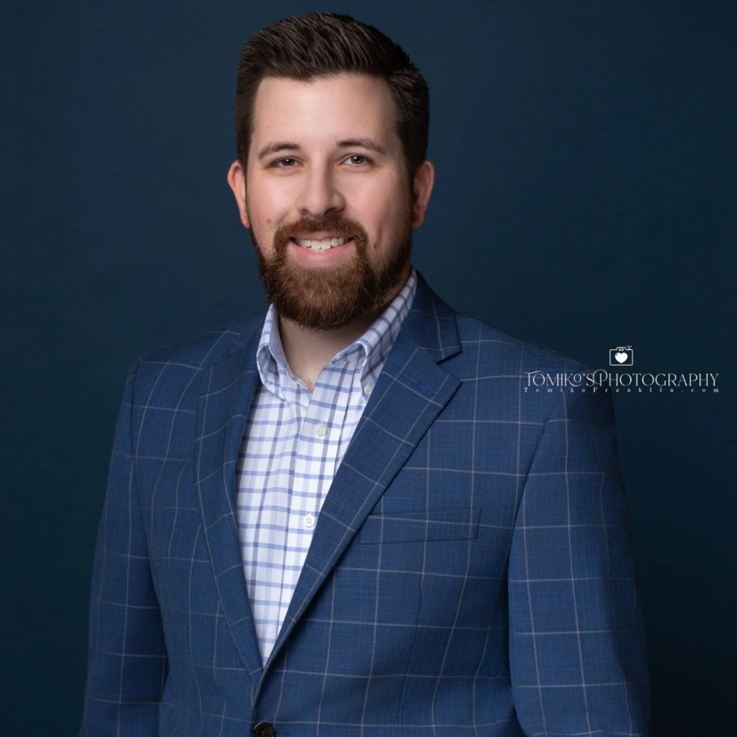 A professional headshot of a man taken in a studio with a blue background at Tomiko's Photography studio in Birmingham, Alabama.