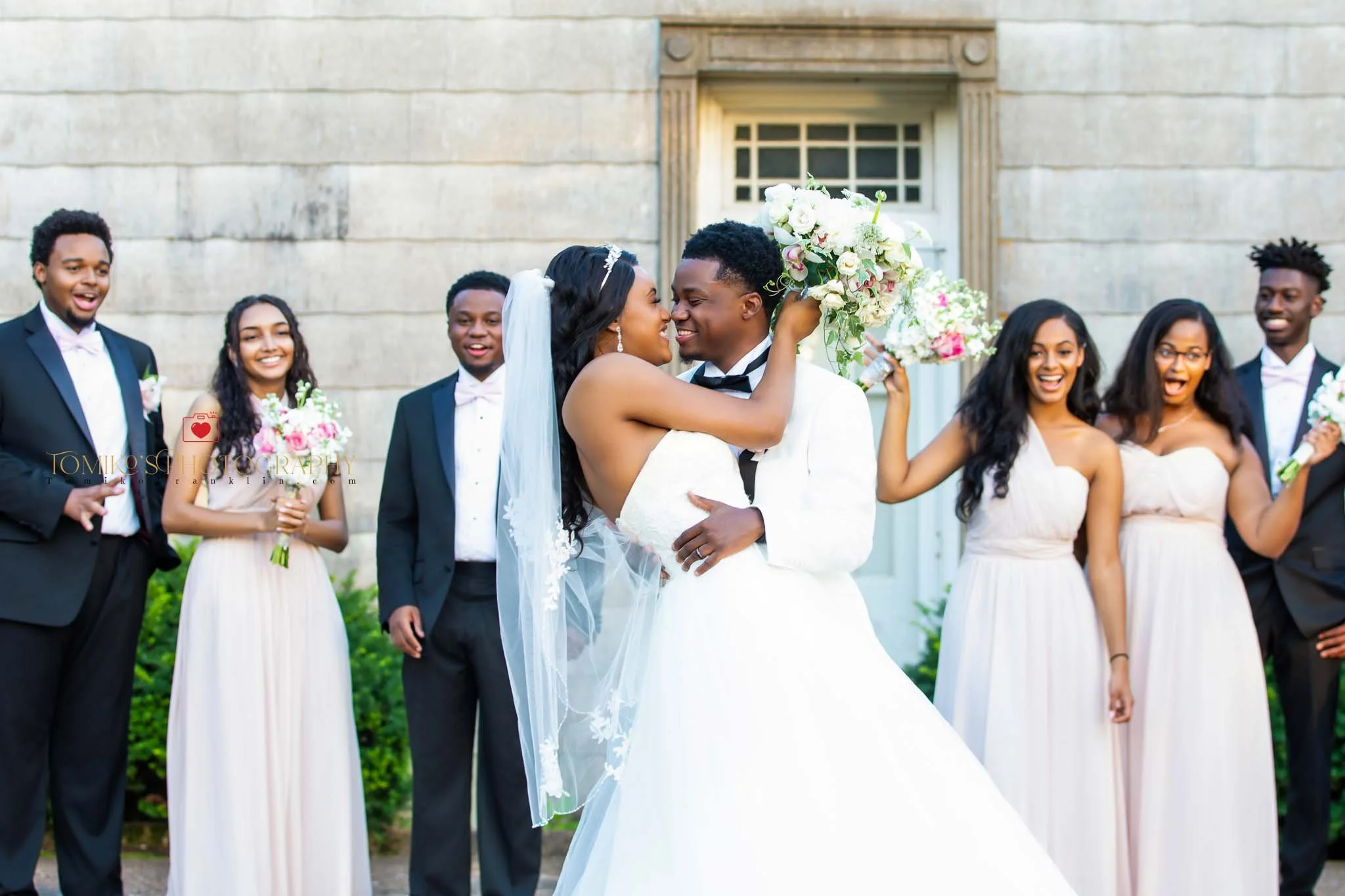 Newlywed couple doing a celebratory dip while their wedding party cheers behind them, captured by an Alabama wedding photographer specializing in joyful, elegant wedding moments.