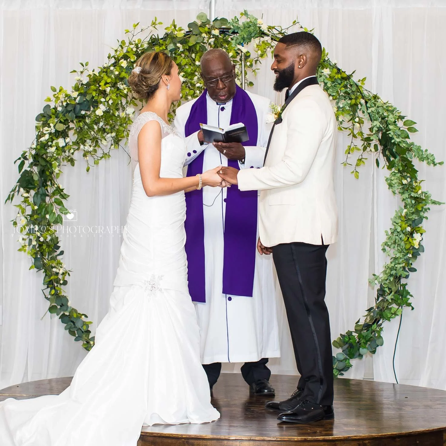 Bride and groom holding hands during their wedding ceremony, exchanging vows in front of the pastor. Elegant, timeless wedding photography captured by a Birmingham AL wedding photographer specializing in polished, editorial‑inspired couples imagery a