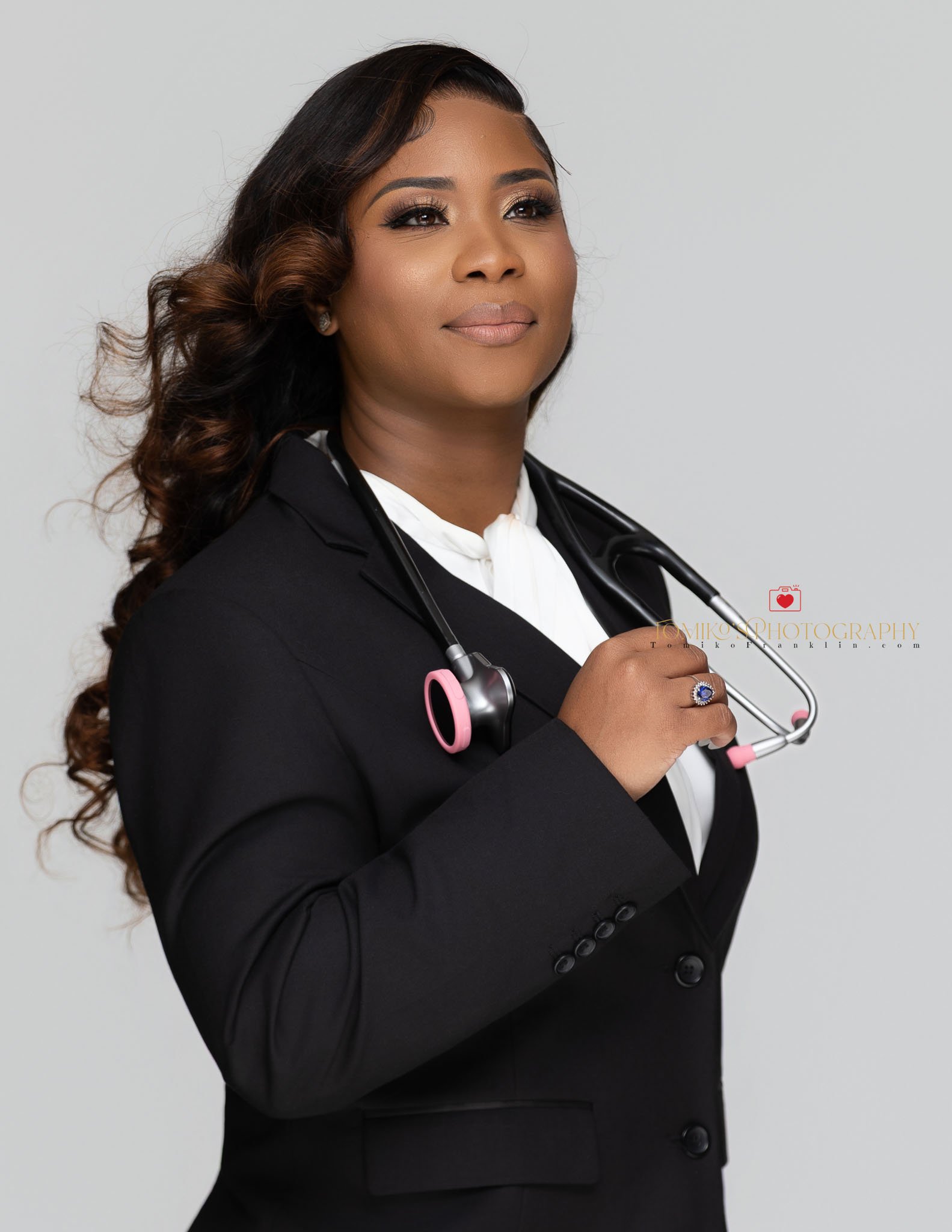 Professional female medical professional headshot of a woman holding a speculum, showcasing a confident and approachable demeanor for team headshot photography.