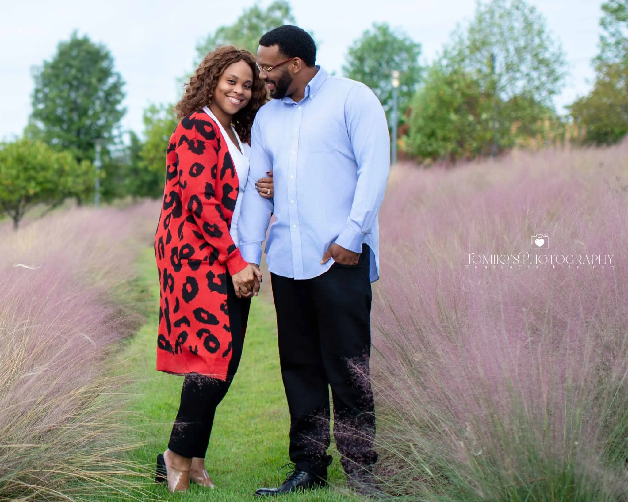 Engagement couple holding hands and smiling during a golden hour session in Birmingham, Alabama, captured by Tomiko’s Photography for modern, romantic engagement portraits.