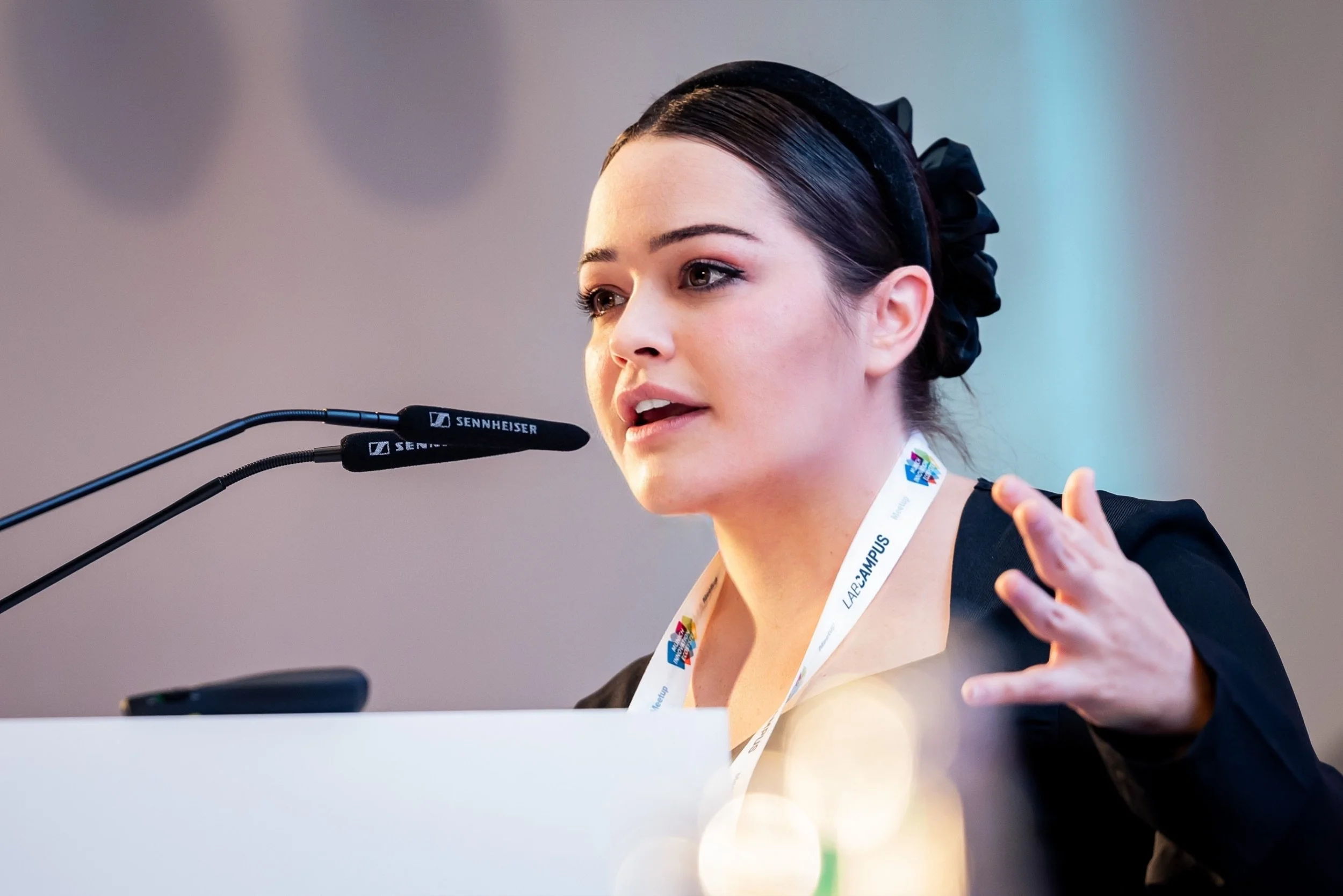 A woman giving a presentation to a humanoid robot in a wood-paneled room.