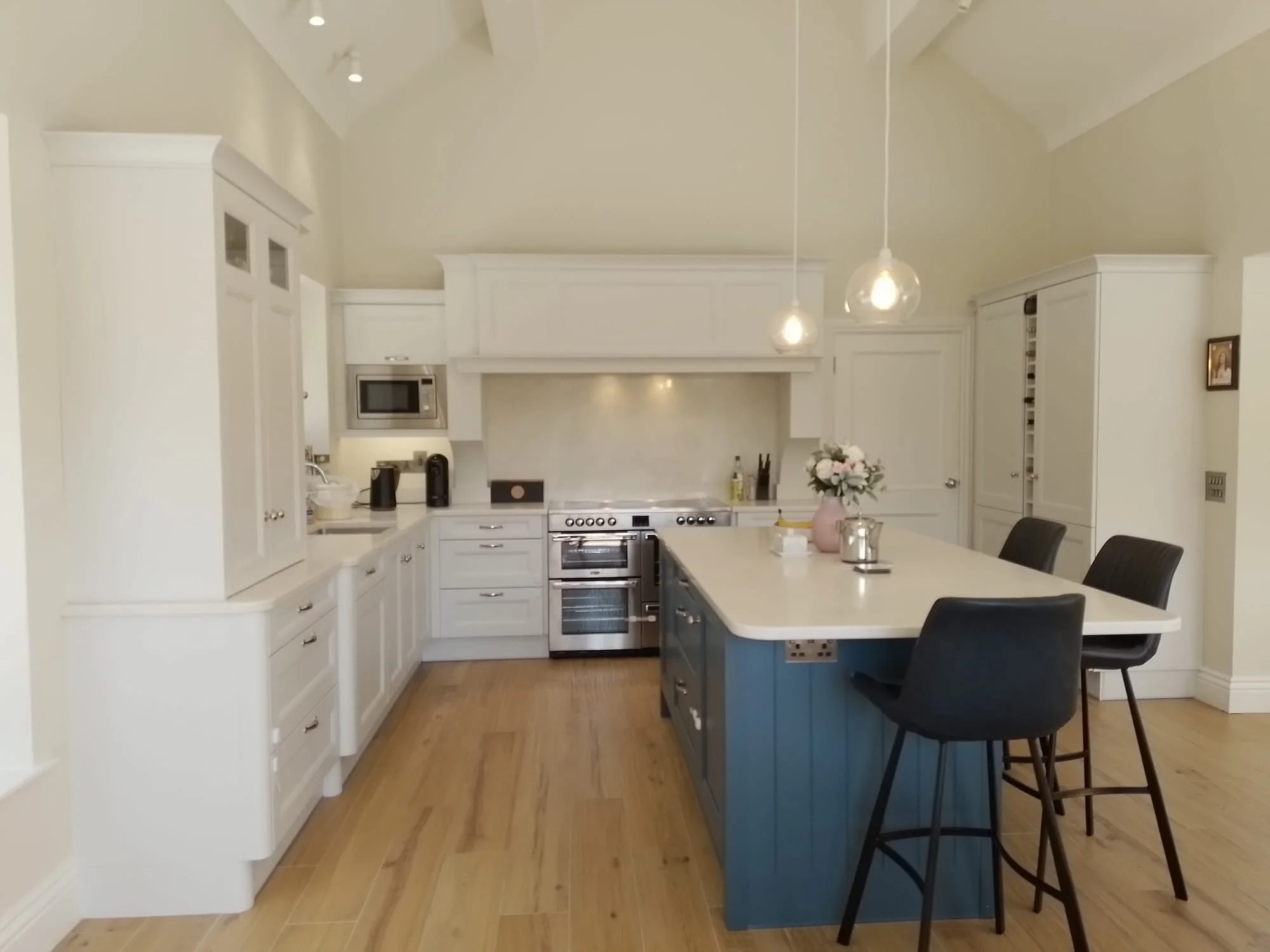 Modern kitchen with white cabinets, blue island, and bar stools