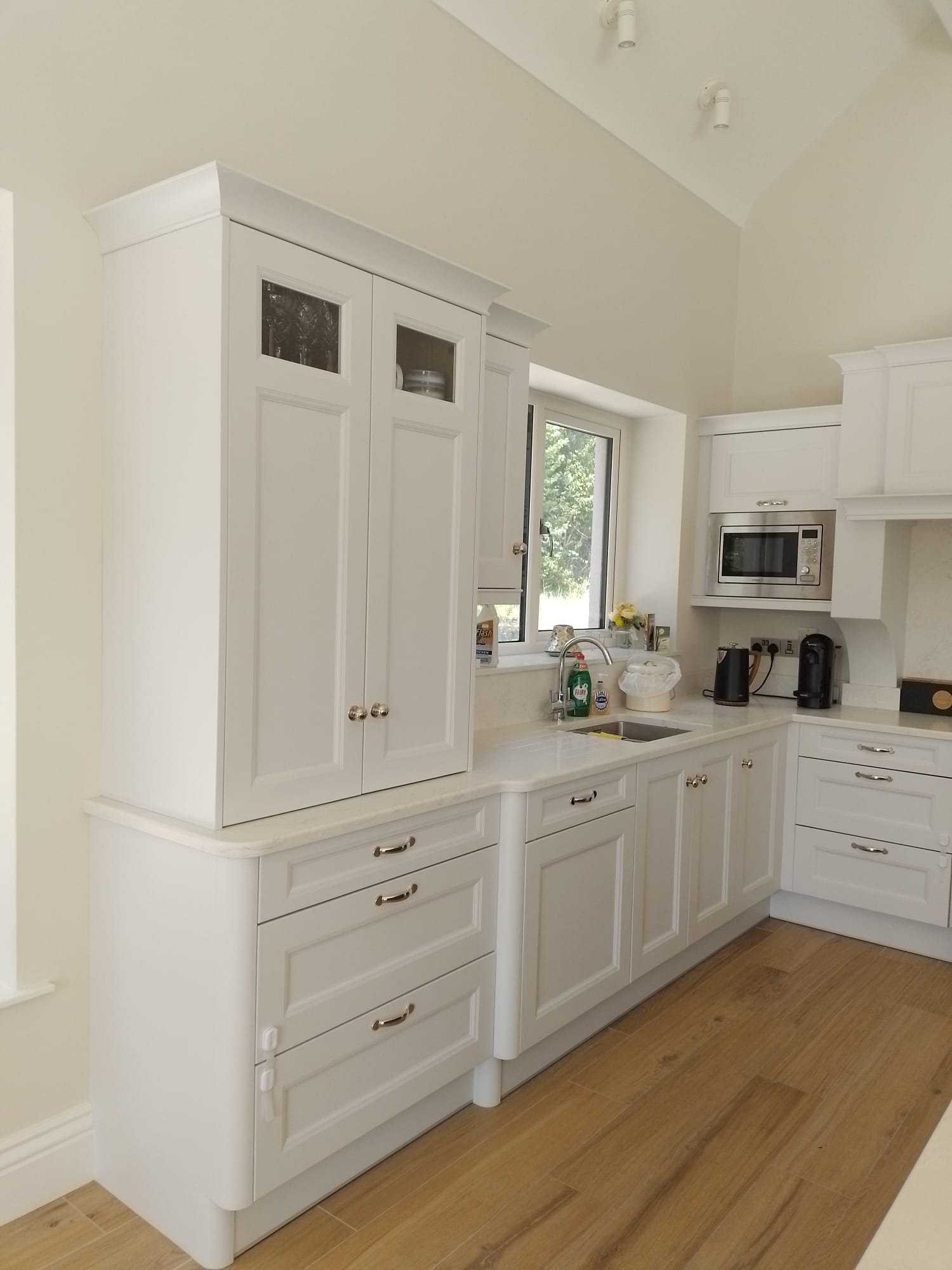 Modern kitchen with white cabinets, wooden floor, and appliances