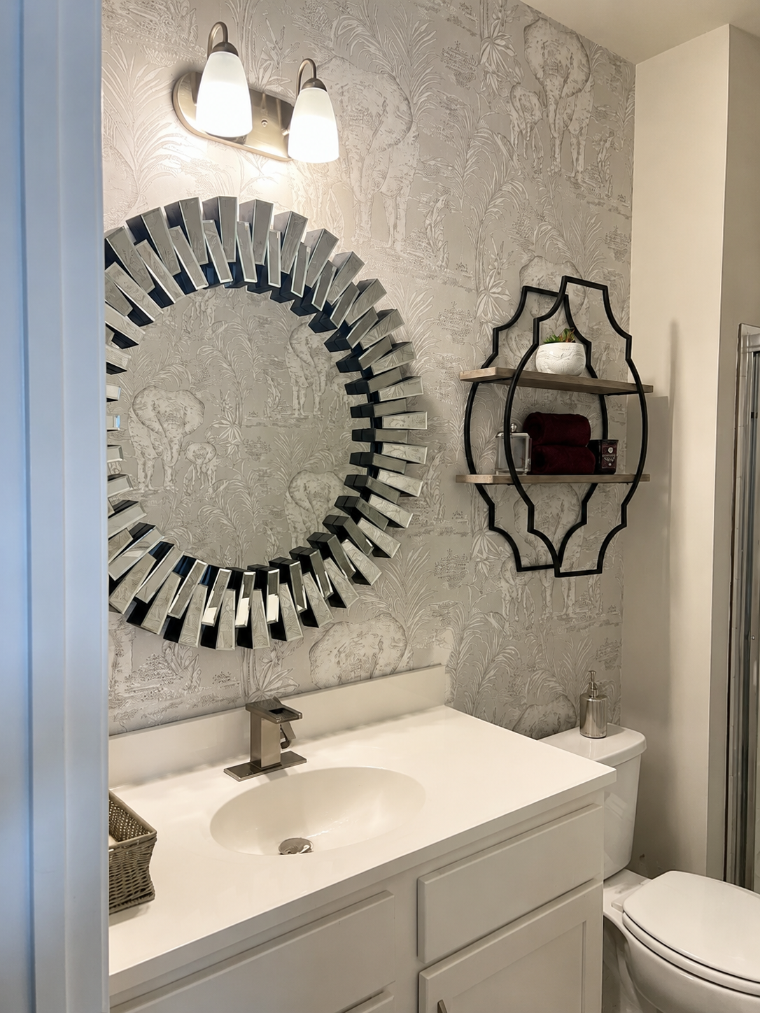 powder room with silver mirror and silver wallpaper with elephants, and floating shelff with decor