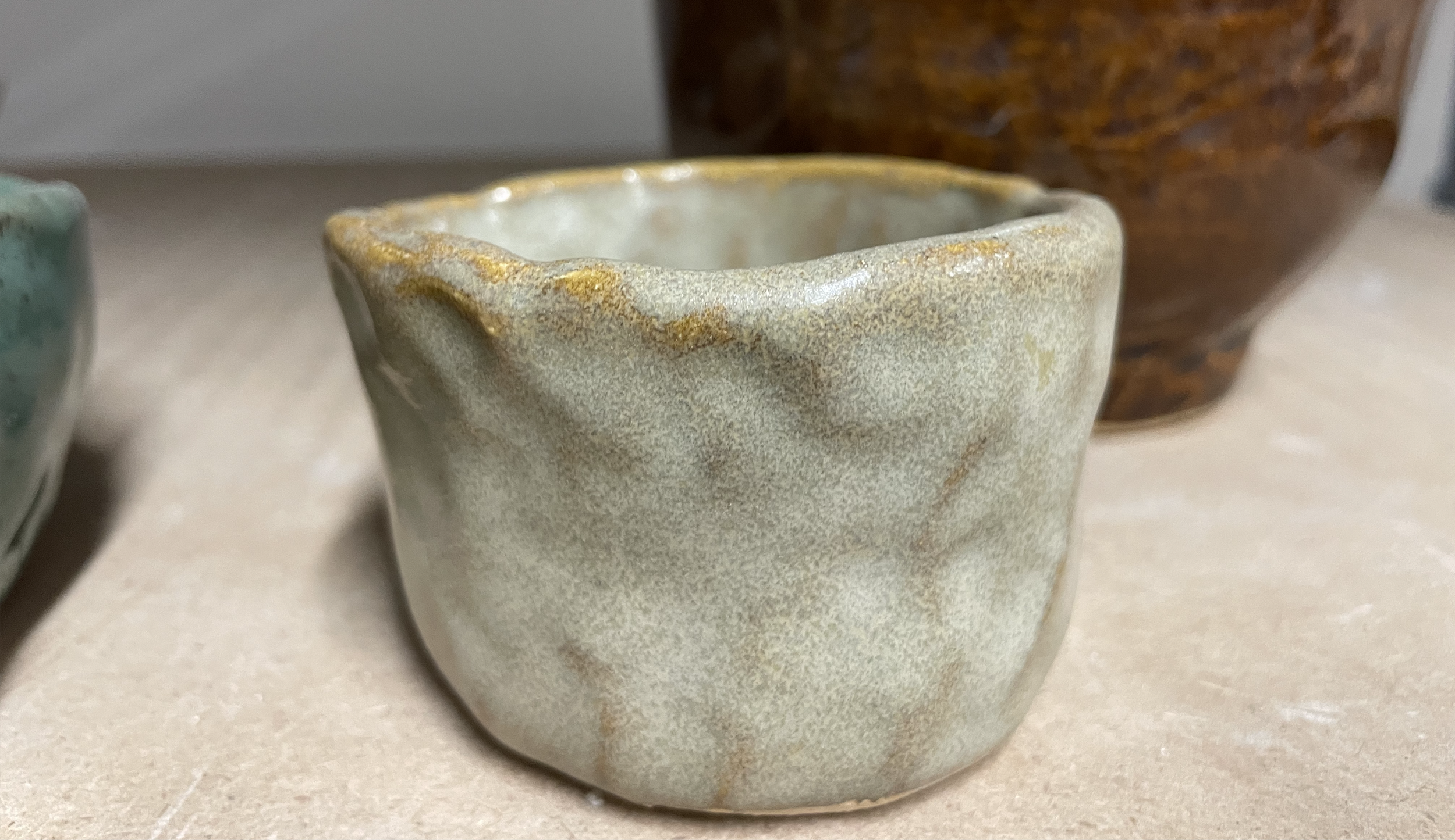 A small, charming hand-made pinch bowl rests on a table top.