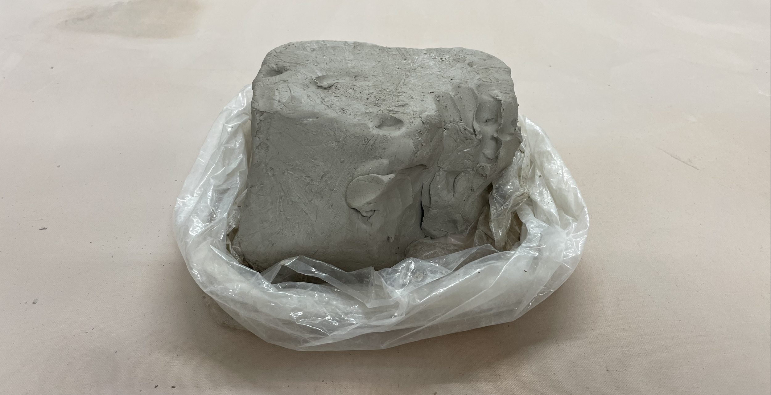 A wet block of unshaped clay sits in an open bag.