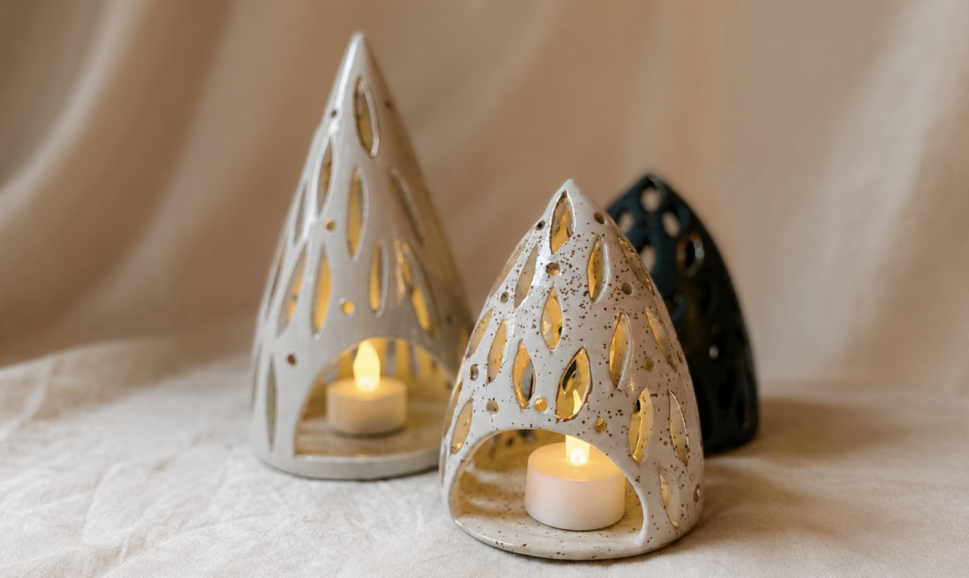 Three handmade ceramic luminaries with tea lights.