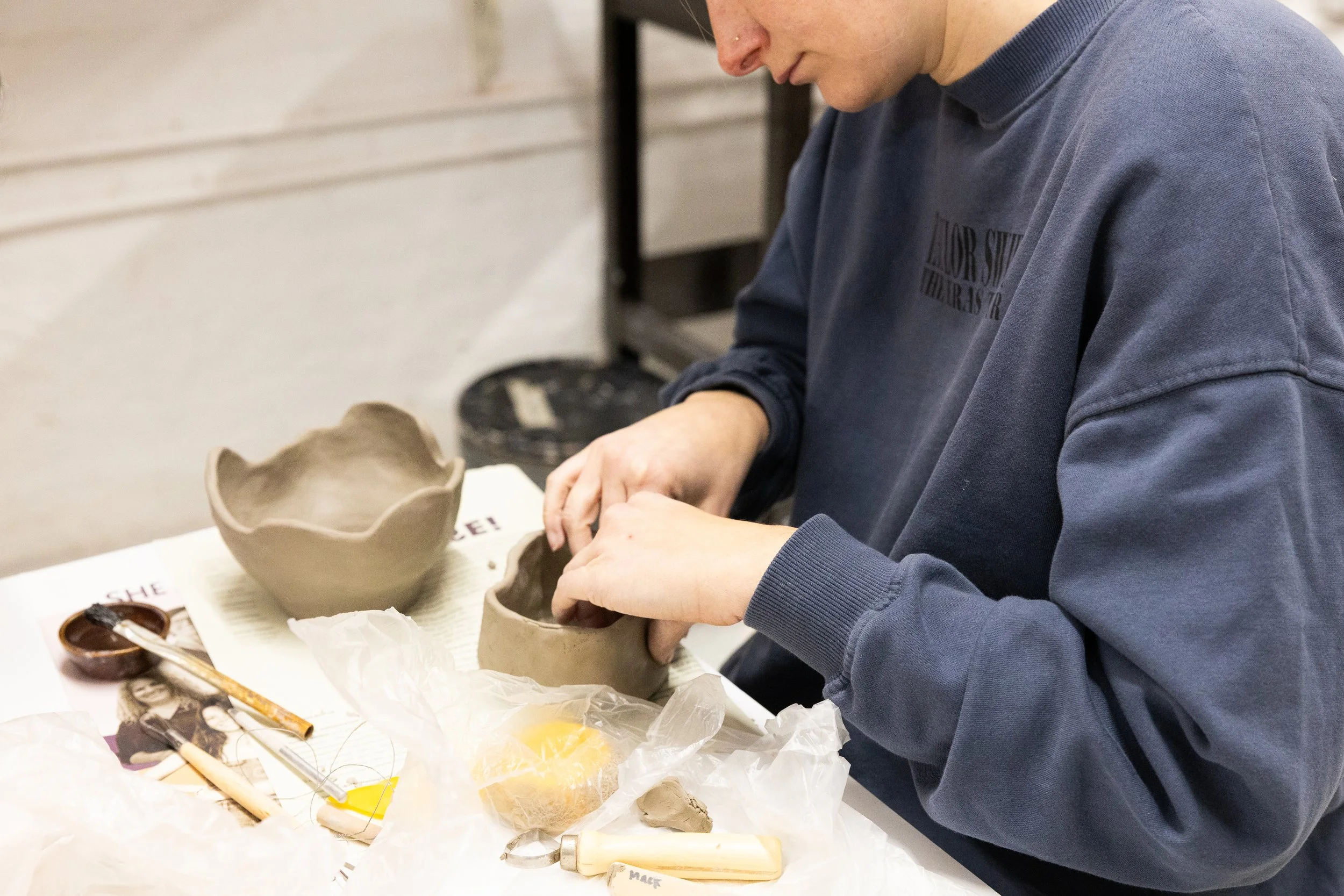 A woman shapes clay into a bowl.