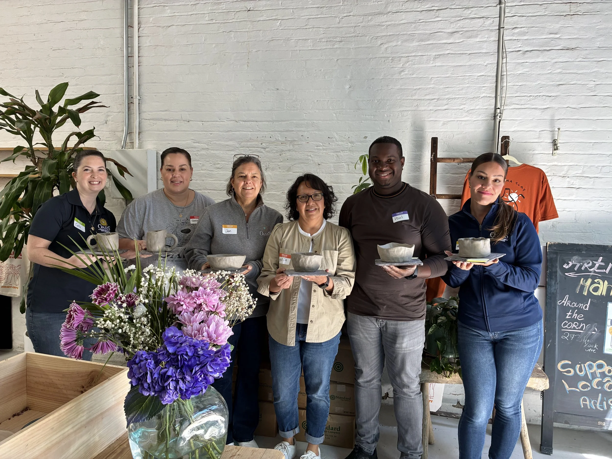 Students in a ceramics class hold their handmade bowls and mugs in Atacama Clay Studio.