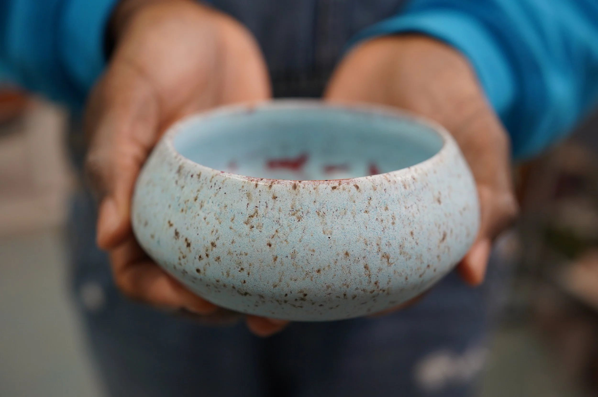 Extended hands offer a beautiful handmade bowl.