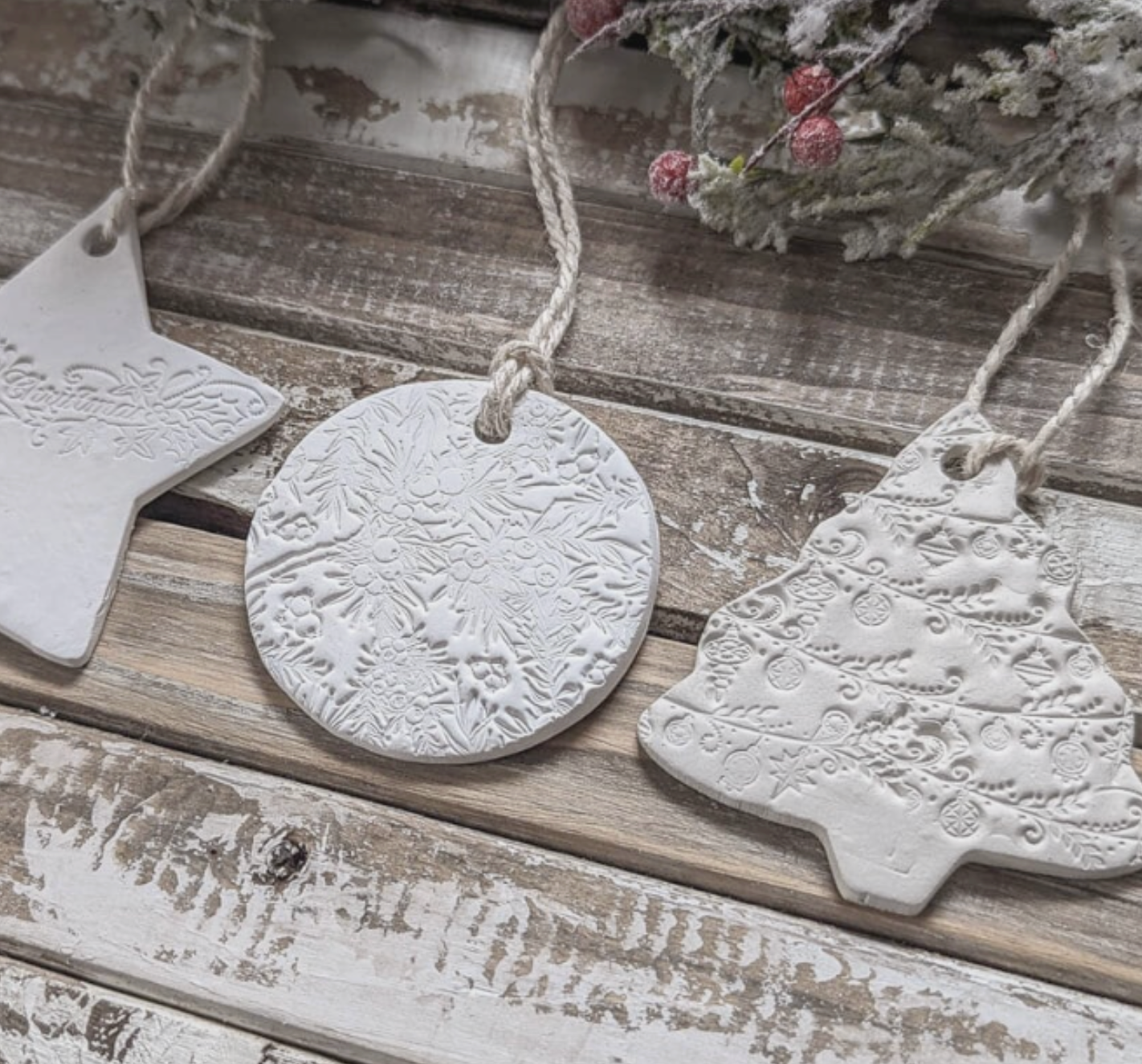 White handmade Christmas ornaments lie flat on a holiday table.