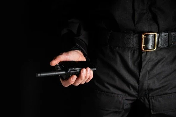 A police officer's hand holding a radio station on his belt, close-up.