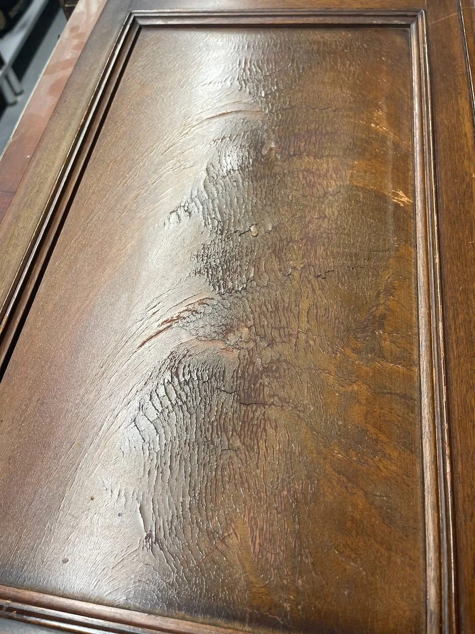 Close-up of a worn and cracked wooden surface with visible grain and finish.