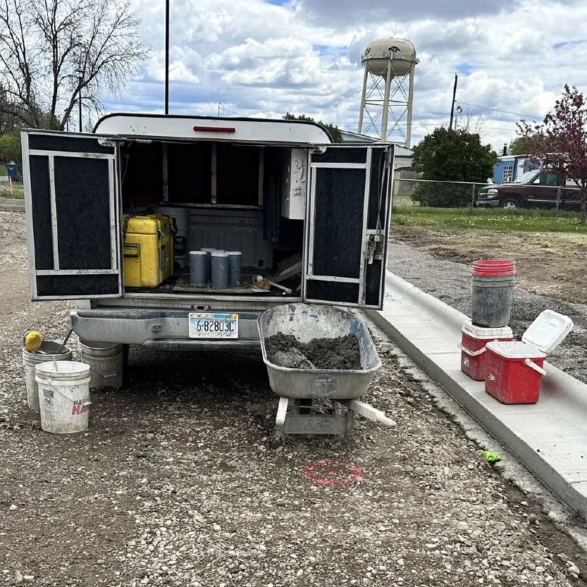 An inspection truck parked at a worksite getting ready for a job with supplies on the sidewalk
