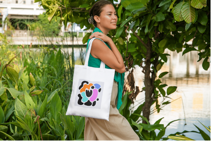 Woman with a colorful tote bag standing near lush greenery.