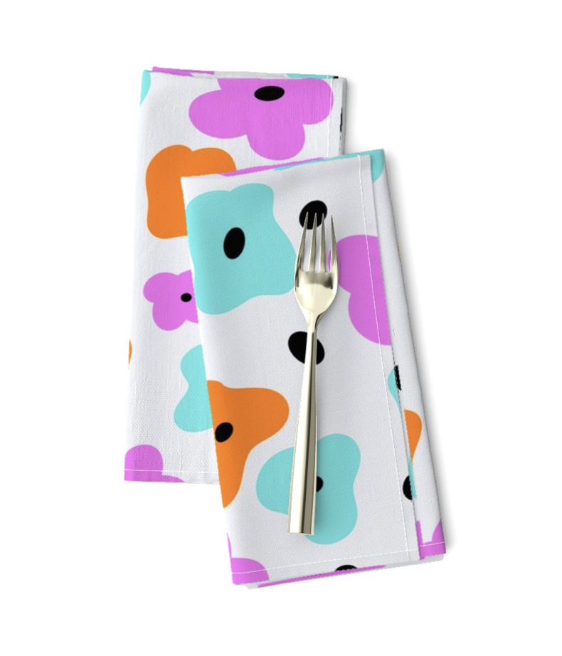 Two folded cloth napkins with colorful floral patterns and a fork placed on top.