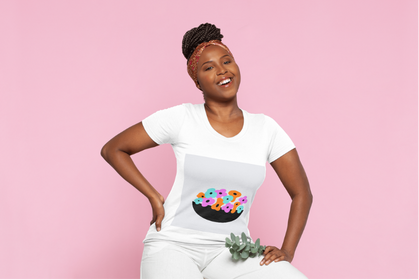Smiling person wearing a white t-shirt with colorful flower design, sitting against a pink background.