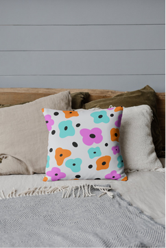Decorative pillow with colorful floral pattern on bed with neutral bedding.