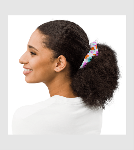 Person with curly hair wearing a white shirt and colorful hair scarf