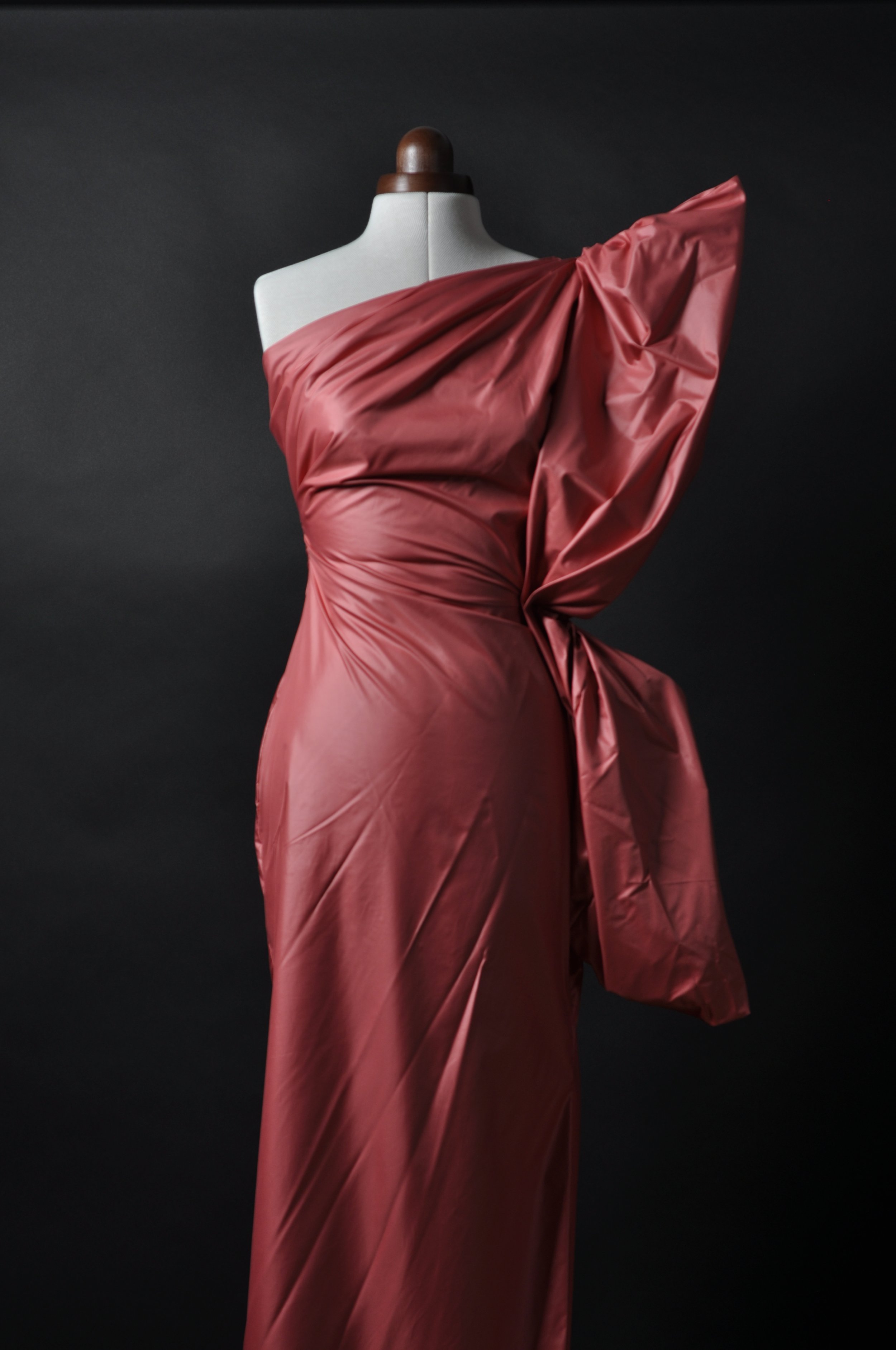 Schneiderpuppe mit einem langen Kleid in rot vor schwarzem Hintergrund, wasserresistenter Stoff, Silhouette mit Schmetterlingsflügel.