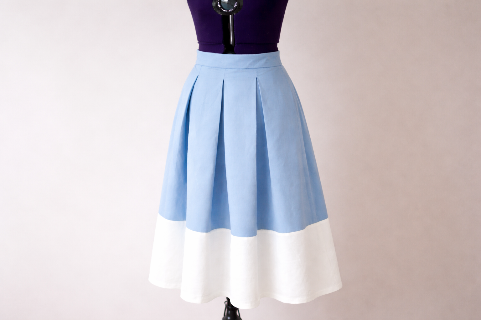 Rock mit Kellerfalten in den Farben blau und weiß, auf einer Schneiderpuppe.