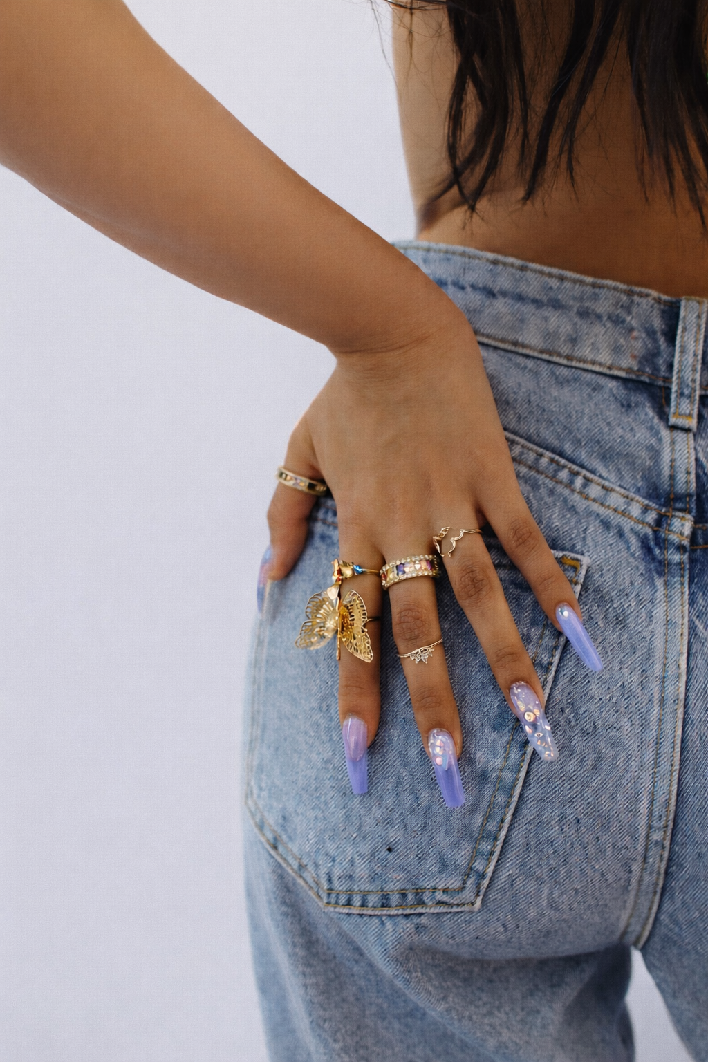 Close-up of a man with glasses, curly dark hair, a beard, and a nose ring, wearing a black sweater with a white shirt underneath, smiling lightly, indoors with a blurred background.