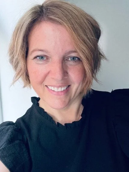 A woman with short blonde hair and blue eyes smiling at the camera.