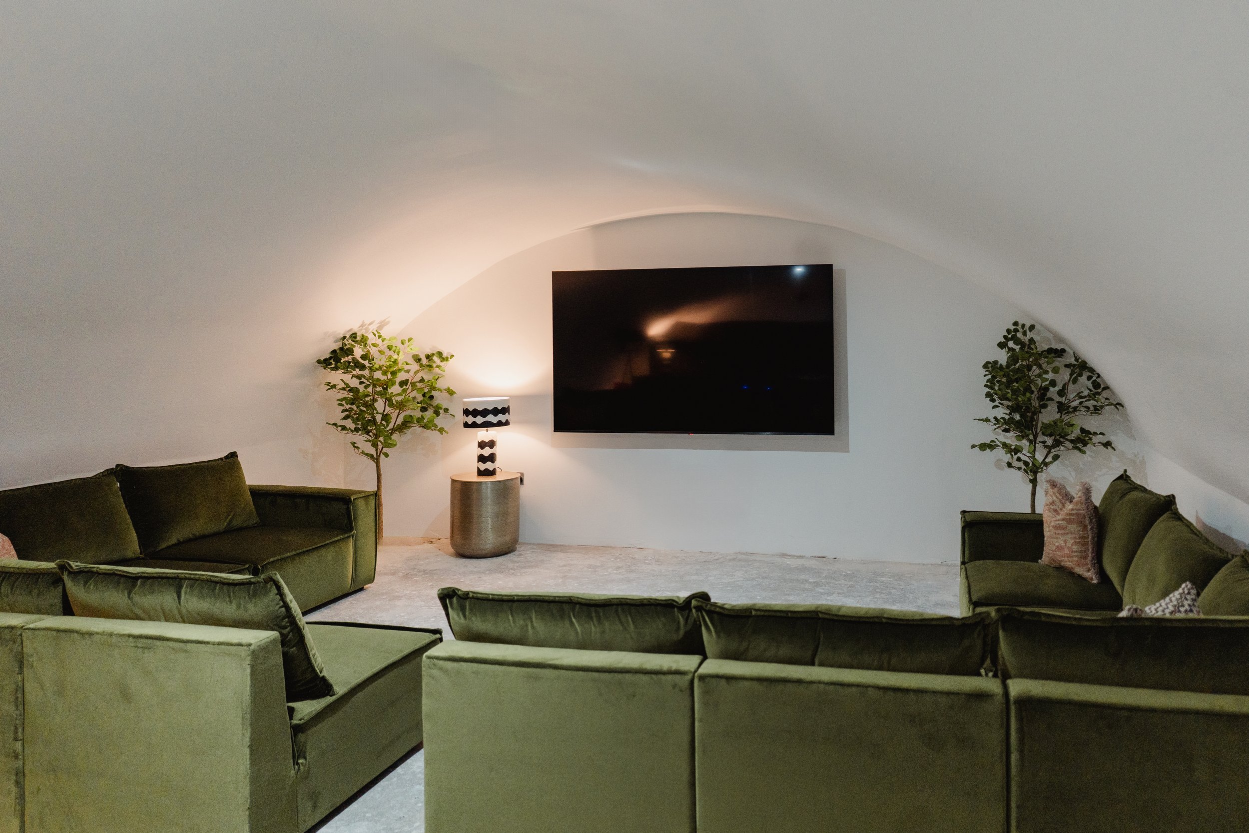 Vaulted cinema room with olive green velvet sofas and wall mounted screen, Niddry Street serviced apartments, Edinburgh