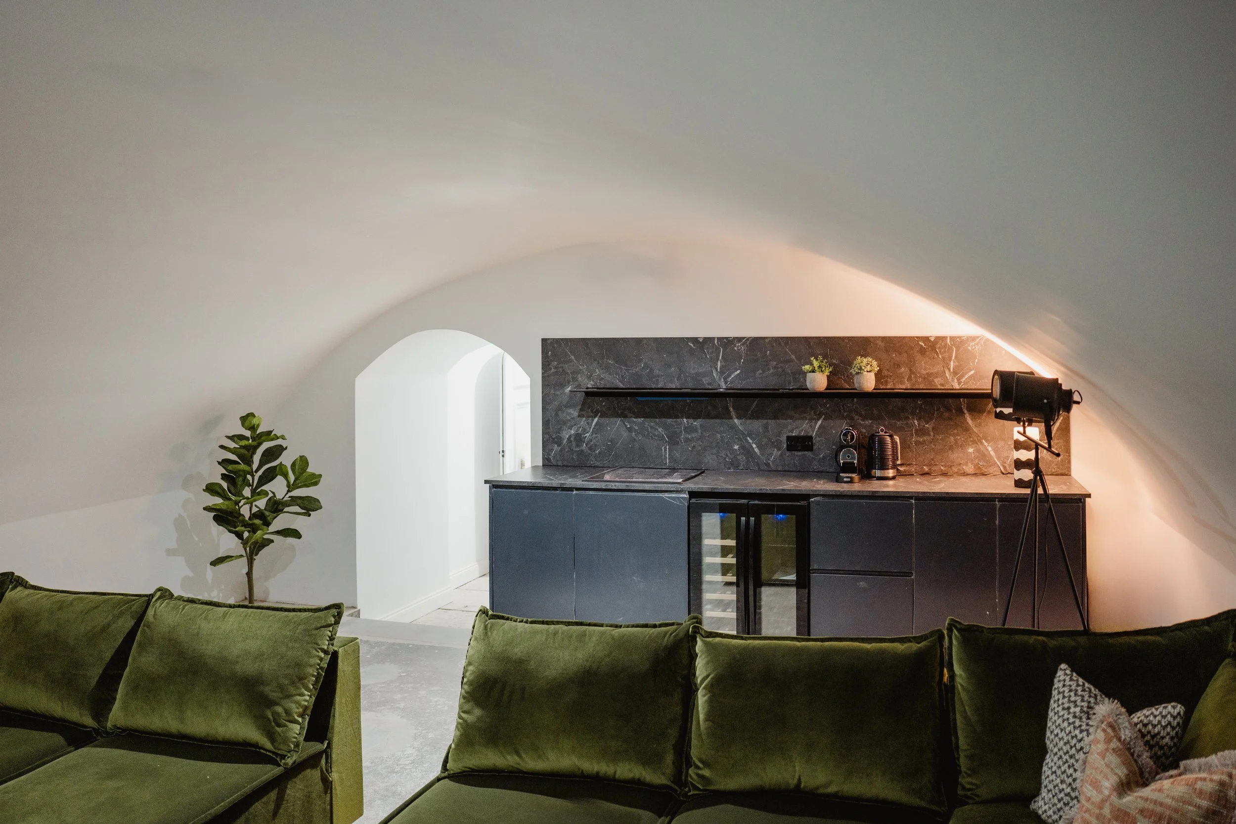 Vaulted cinema room with green velvet sofas and a dark bar area, Niddry Street serviced apartments, Edinburgh