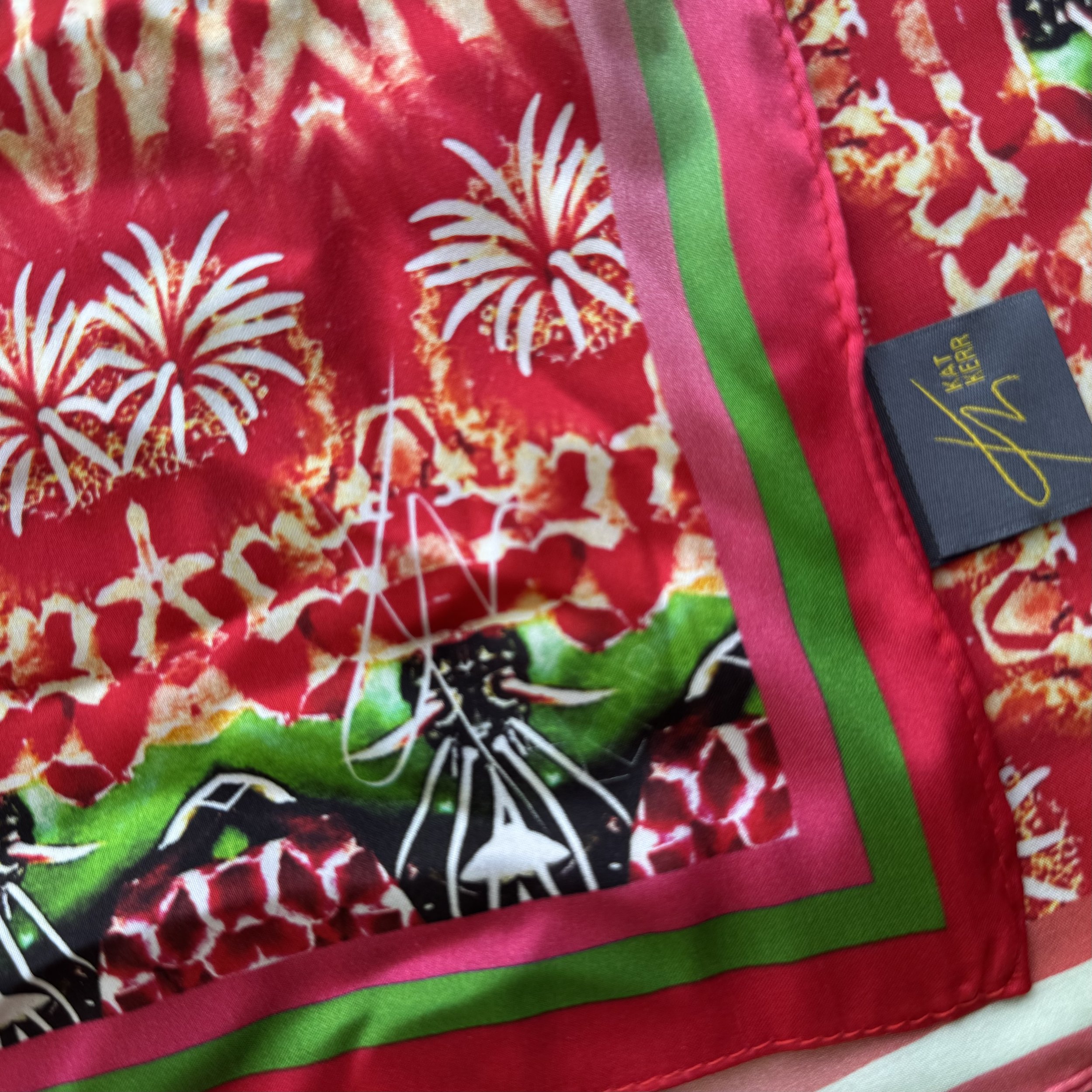 Detail of the corner of "the flowering Desert" red scarf showing texture, hand sewn edge, logo and label.