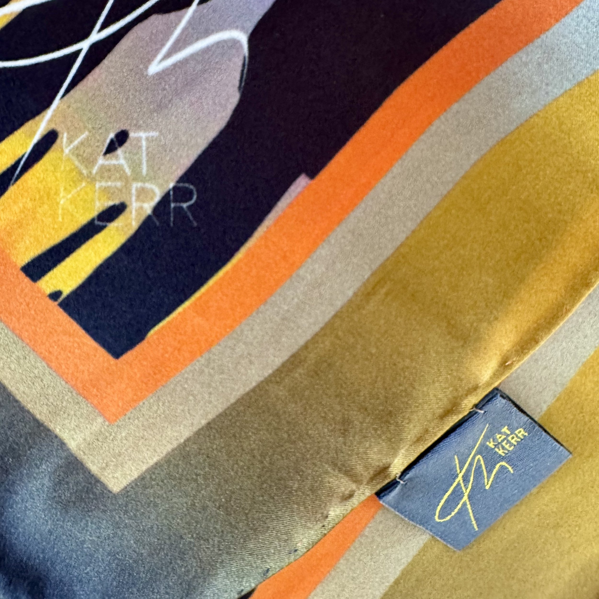 Corner edge detail of "Sunset Sentinels" showing striking colours, lable and logo, satin texture, quality of double sided printing and hand sewing.