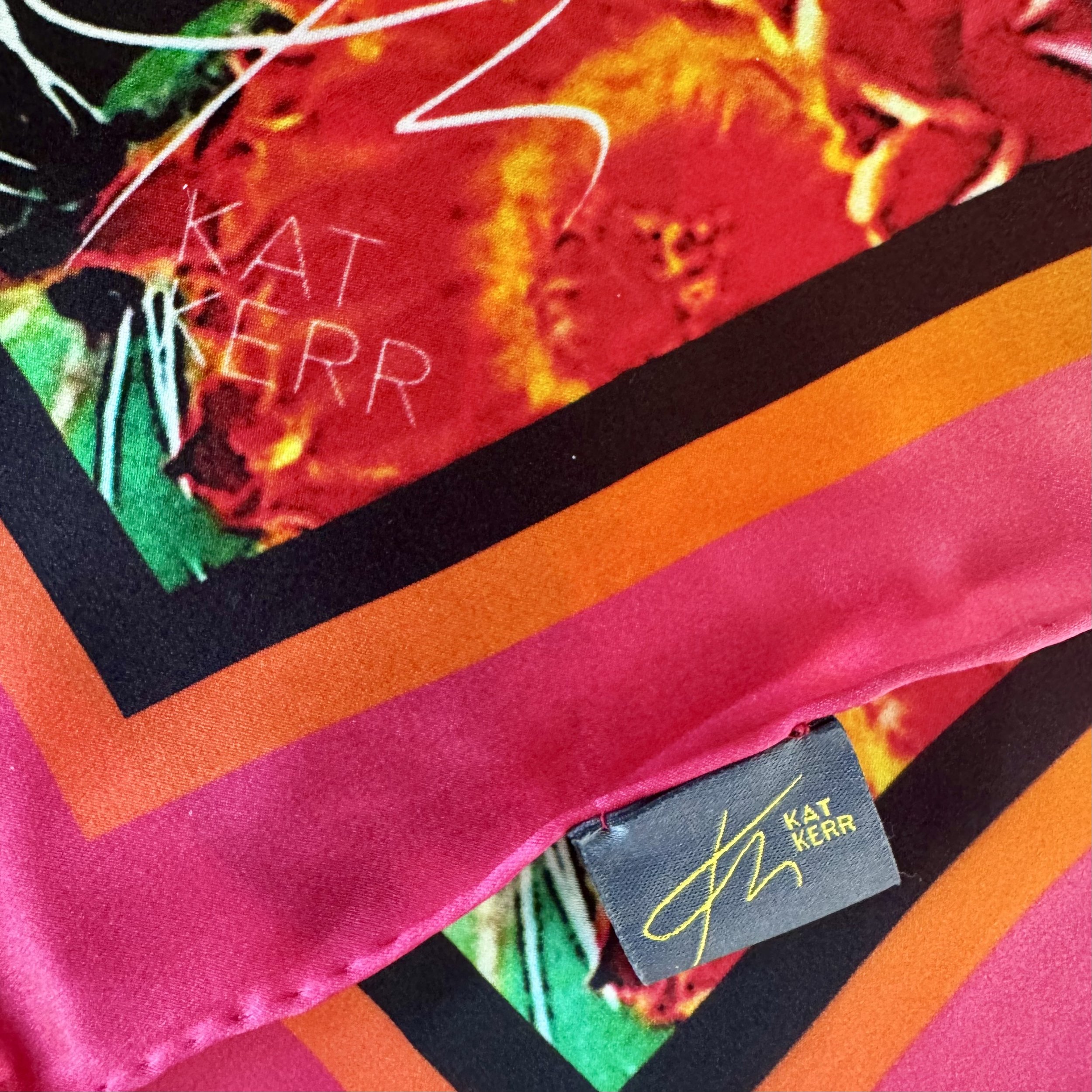 Corner edge of "Phoenix" silk scarf showing brilliant colours, double sided printing, hand sewing, logo and label