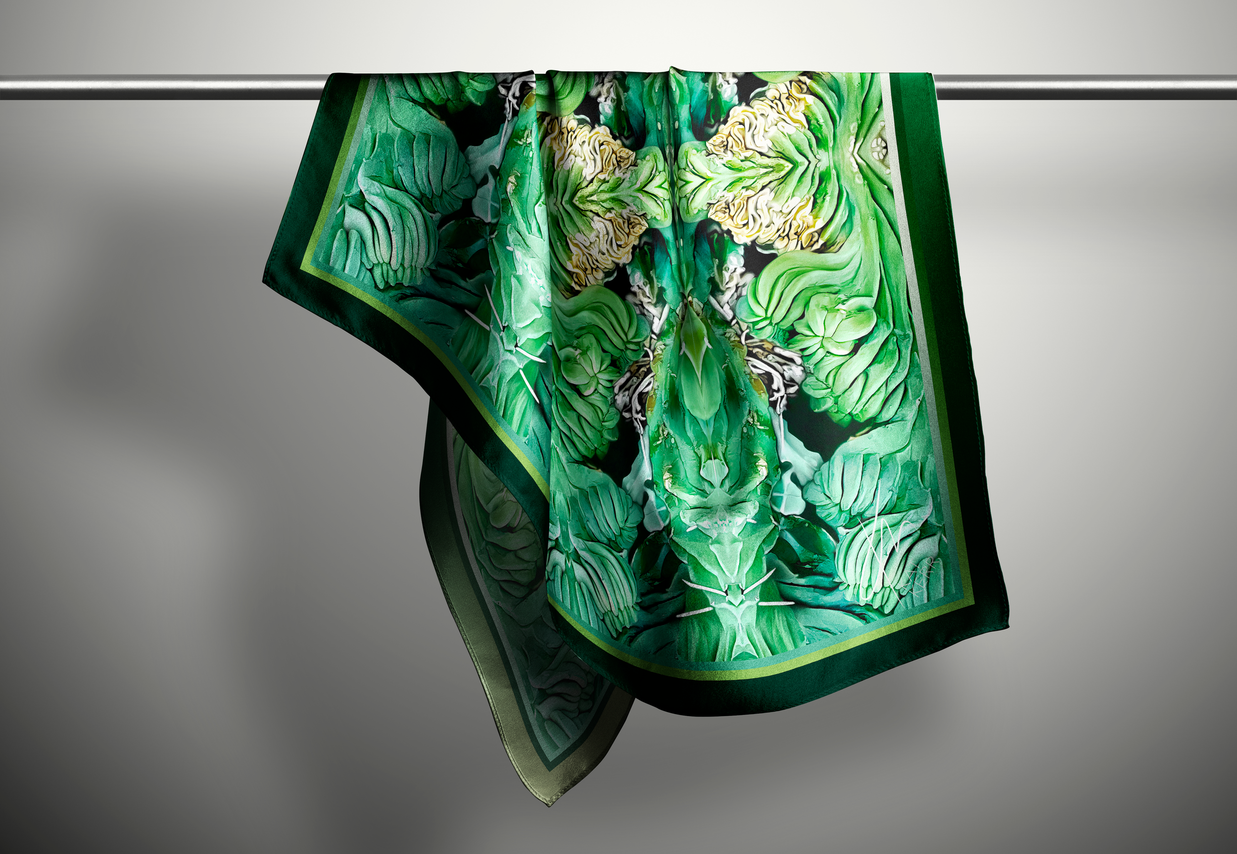 A richly coloured green scarf hangs on a rod in a light grey background