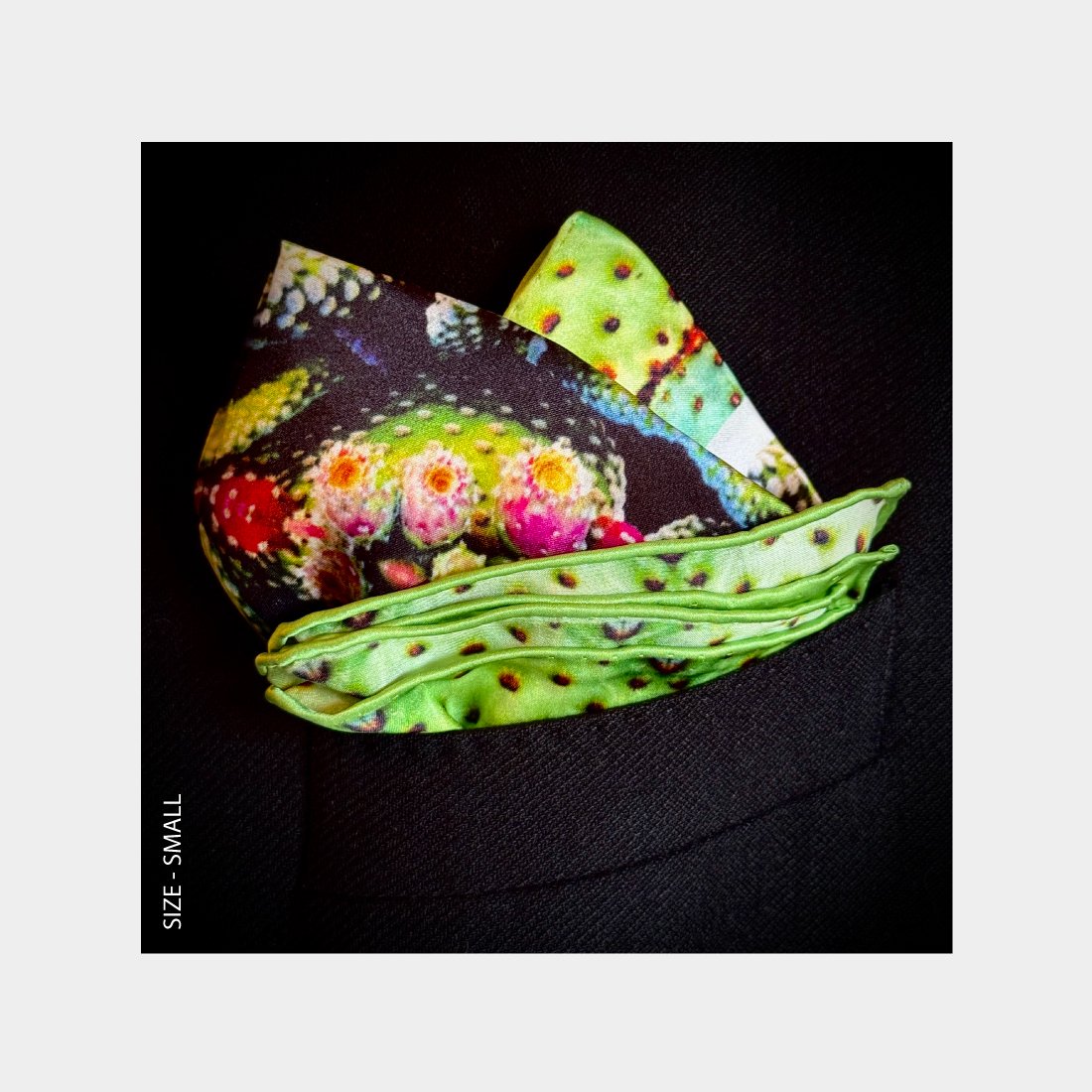 "Exotic Fruit" is shown as a Pocket Square bursting pink and green patterns from the breast pocket of a black wool jacket.