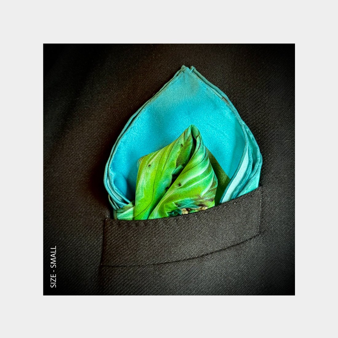 "The Life of Water" is shown as a silk Pocket Square flowering with jewelled toned blues and greens from the breast pocket of a black wool suitjacket.