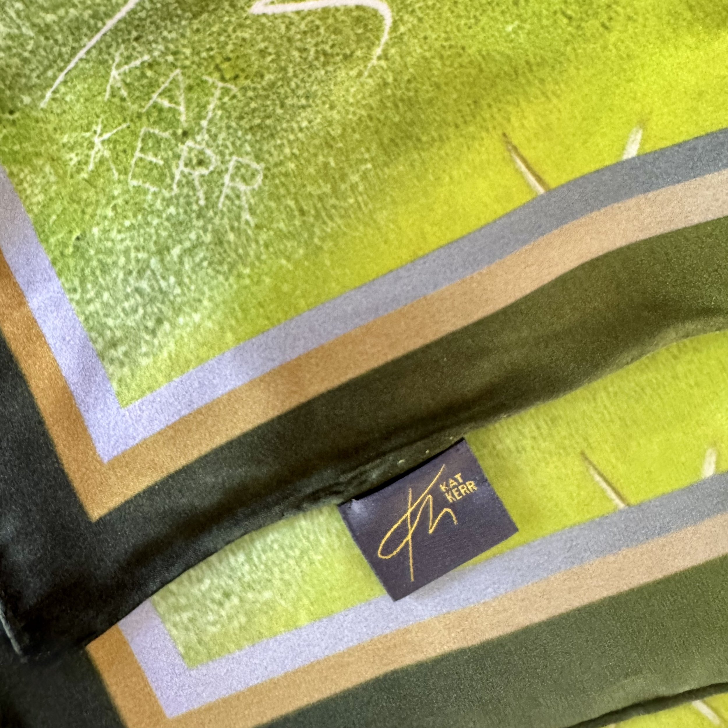 Corner edge of "Diversion" silk scarf showing logo, label, double sided printing, textures and hand sewing