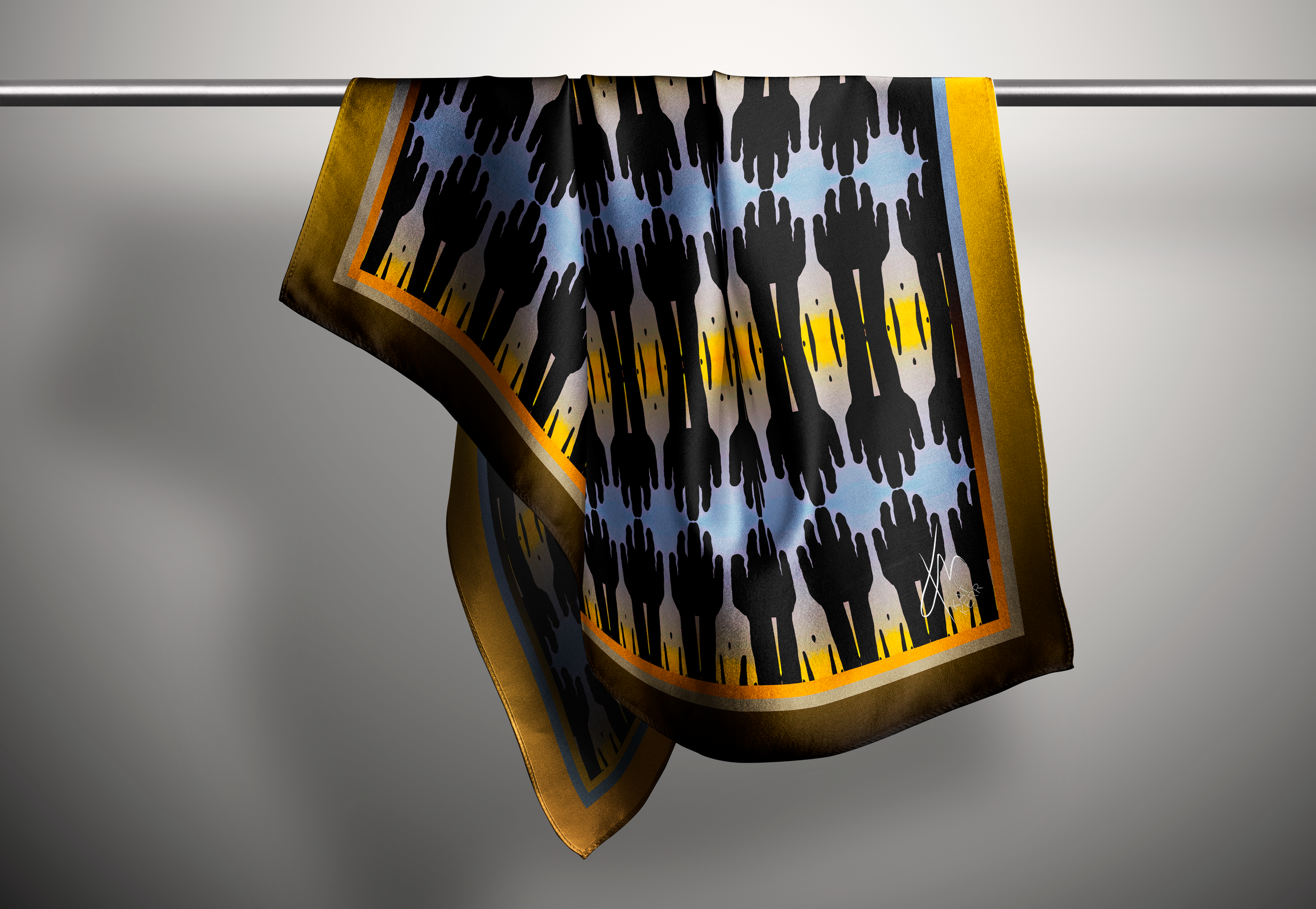 A boldy graphic silk scarf hangs from a rod in a pale background