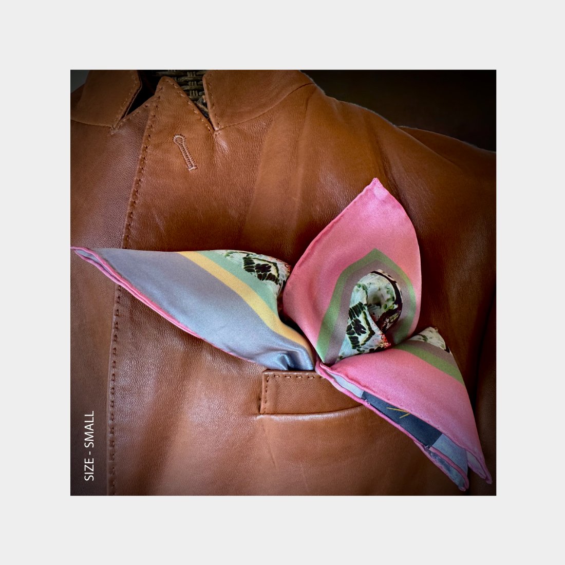 "Sweet Succulents" silk scarf is shown as a Pocket Square adding pink patterns cascading from the breast pocket of a brown leather jacket