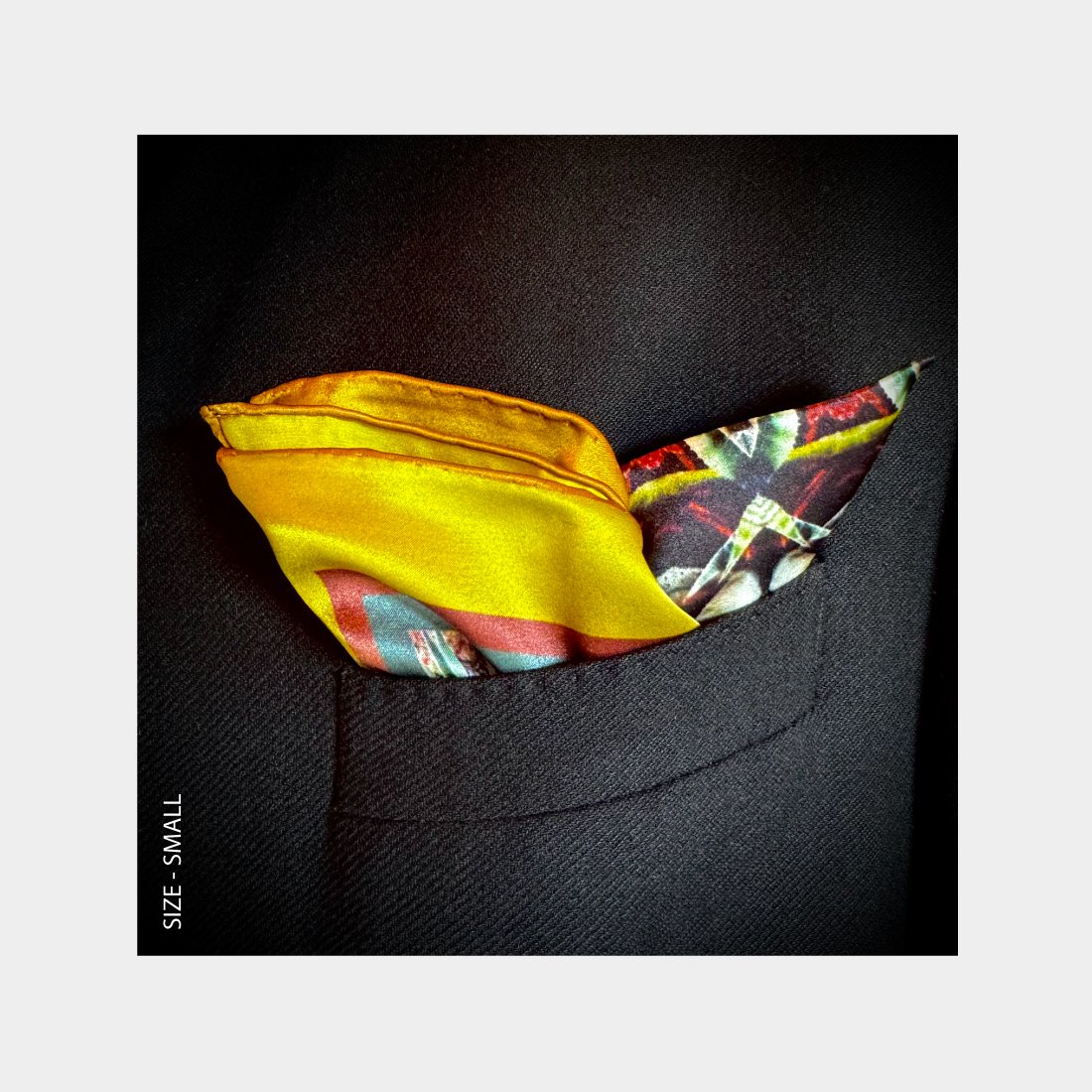 "Metamorphosis" is shown as a Pocket Square offering a burst of brilliant yellows and reds from the breast pocket of a black wool jacket.