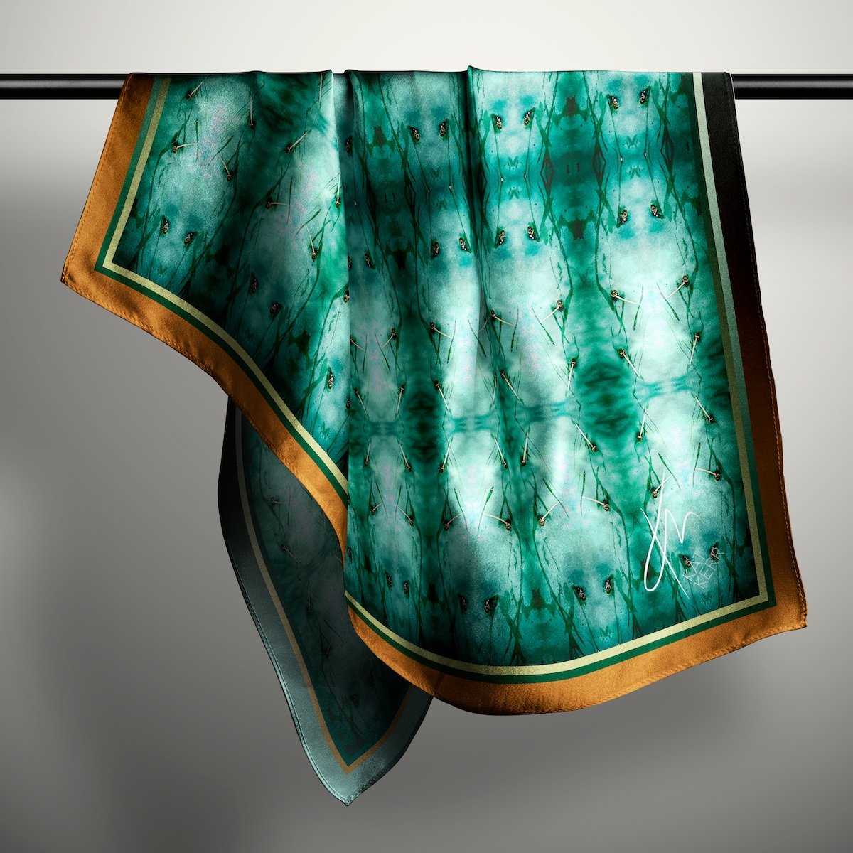 A silk scarf in cool turquoise hangs on a rod in light coloured empty space