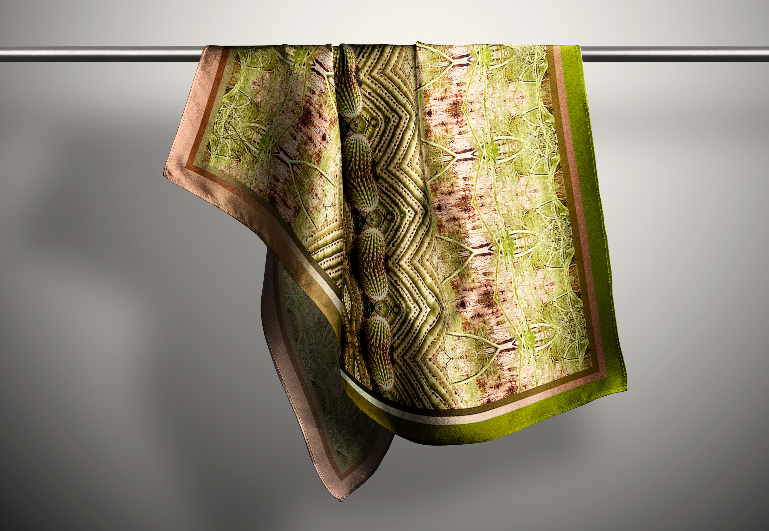 a grass green intensely pattern scarf hangs on a rod in a grey space.