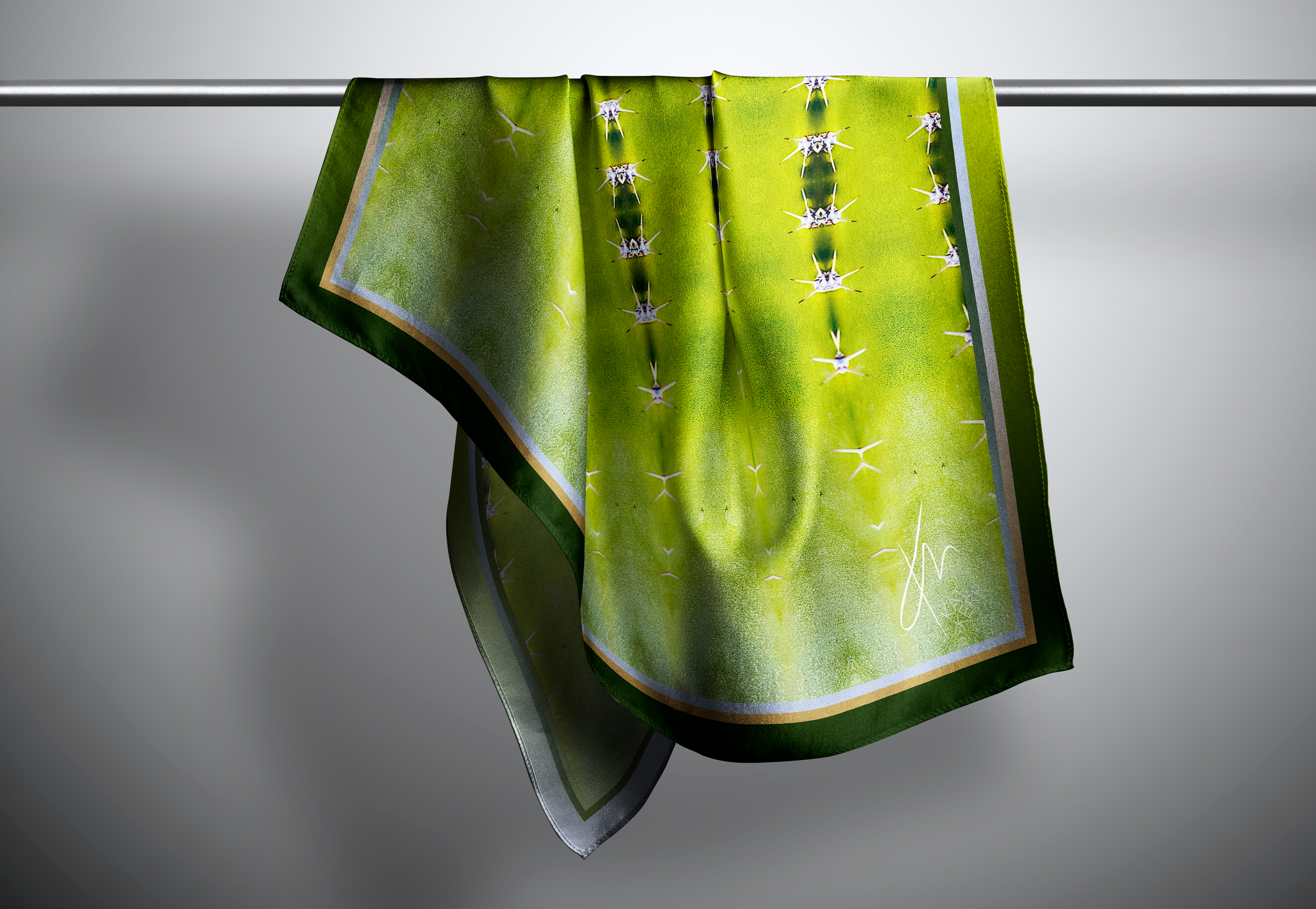 A simple bright green scarf hangs from a rod in a grey space.