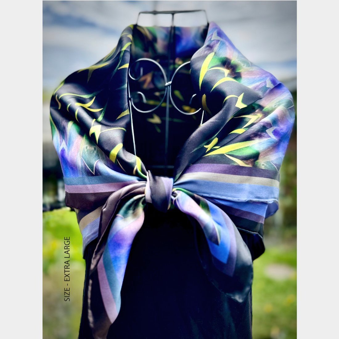 "Centuries of Healing" silk scarf size extra large is wrapped around a wire mannequin and tied in a bow over the bodice of a black top