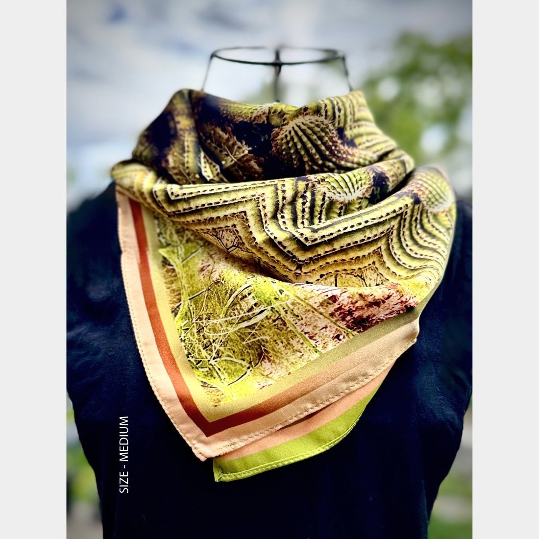 "Roots" silk scarf in size medium is shown draped over the breast of a mannequin wearing a black top.