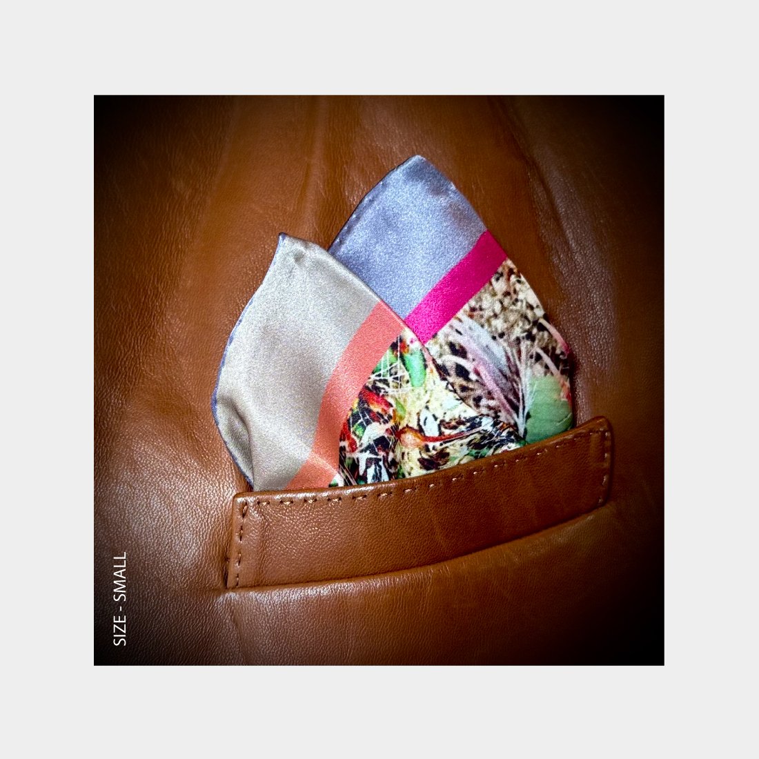 "Desert Blooms" is shown as a Pocket Square offering a burst of floral tones from the breast pocket of a brown leather jacket.
