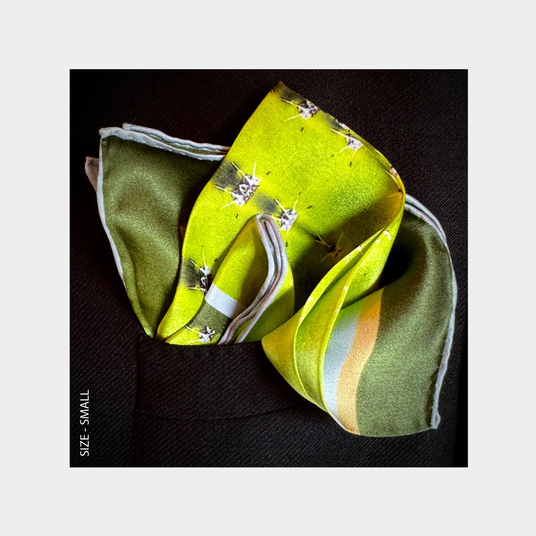 "Diversion" is shown as a Pocket Square bursting with lime green tones from the breast pocket of a black wool jacket.