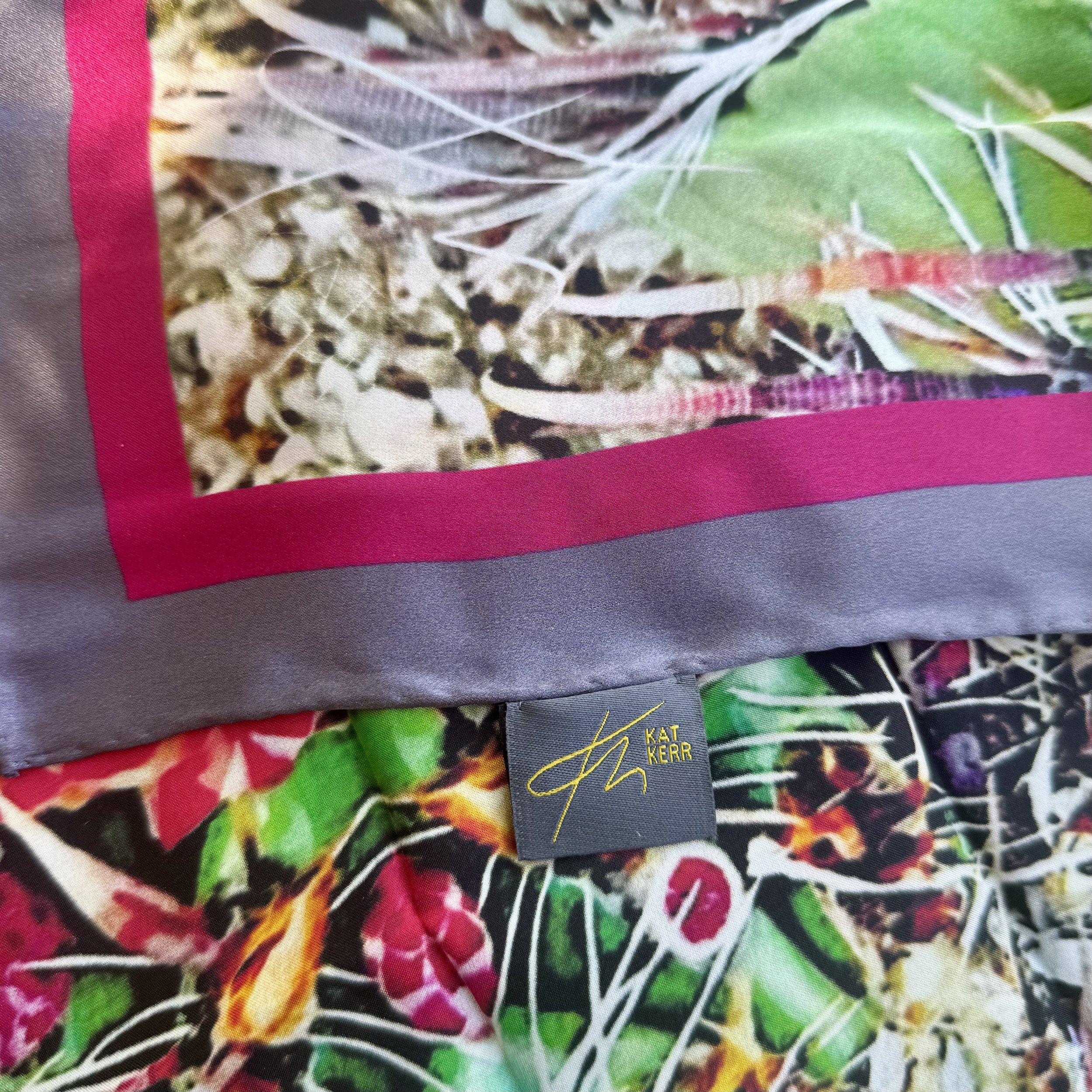 Detail of "Desert Blooms" silks scarf showing double sided printing, hand sewn edges, texture, logo and label
