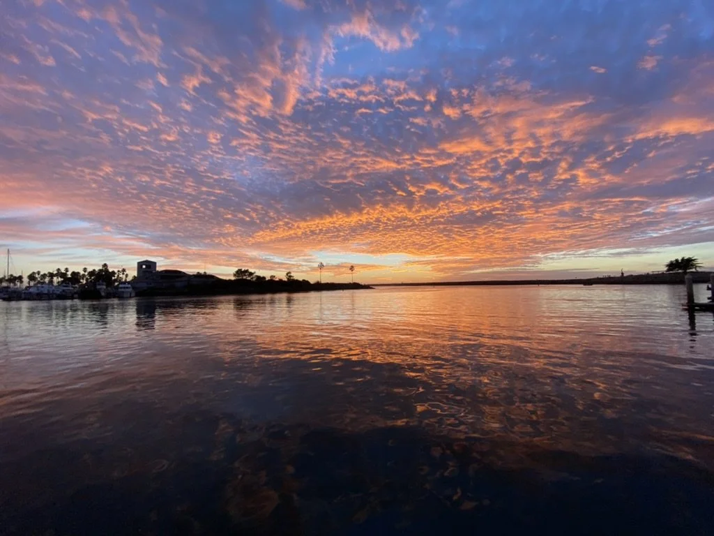 Sunset over a calm body of water with colorful clouds in the sky.